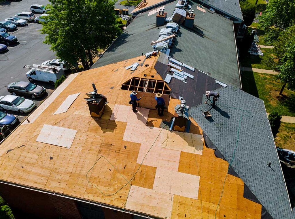 Homeowner reviewing roof damage photos and an insurance policy at a kitchen table.