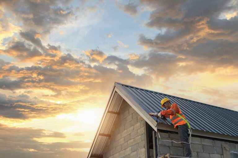 Homeowner examining roof shingles and attic sheathing with a flashlight after winter weather.